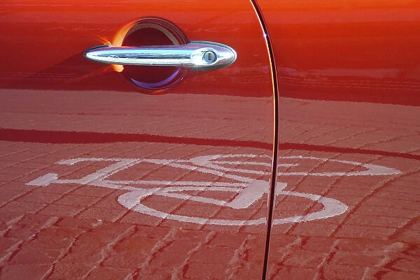 Red car door reflecting a pictogram from a bicycle lane