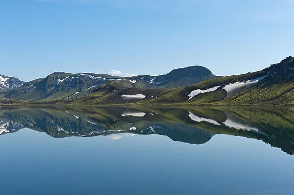 Reflection in the still lake, remnants of snow, panoramic mountain landscape at Alftavatn lake, Laugavegur trekking route, Highlands, Sudurland, Iceland