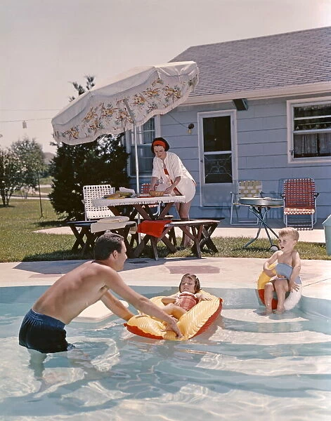 Retro Family In Backyard, Showing An In-Ground Swimming Pool, Father, Mother, Son