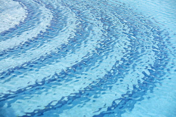 Rippled water surface in a swimming pool, detail, blue with steps below the surface