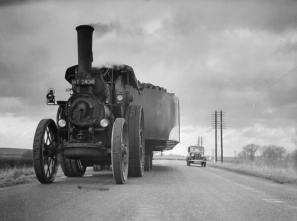 By Road. February 1936: A traction engine pulling an all metal barge on the road to London