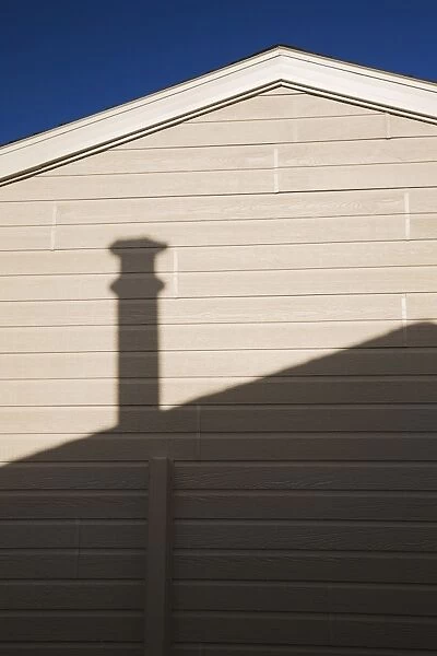 Roofline and chimney shadow on the exterior side wall of a residential home, Quebec, Canada