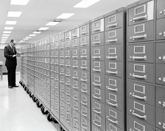 Framed Print : Row of metal filing cabinets on casters, man standing at end of row, with drawer open Framed Print : Row of metal filing cabinets on casters, man standing at end of row, with drawer open