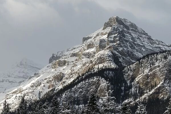 Rugged mountain peak with snow under a cloudy sky