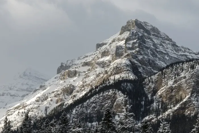 Framed Print : Rugged mountain peak with snow under a cloudy sky