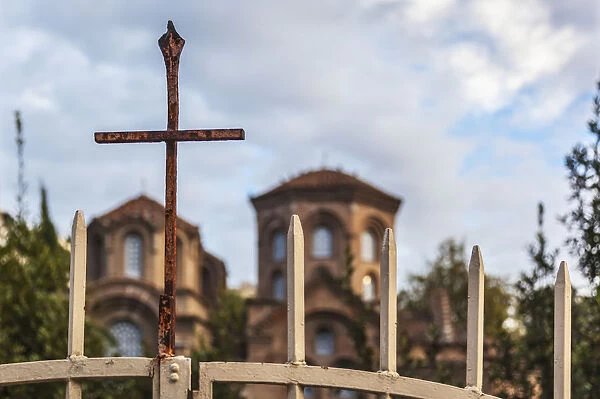 A rusty cross on a gate in front of a church