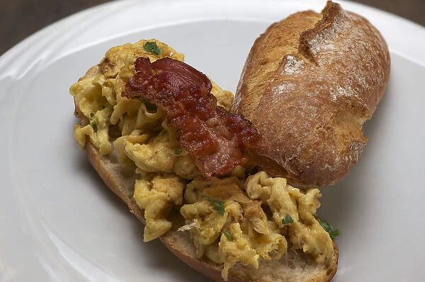 Scrambled eggs with fried bacon on a rustic roll