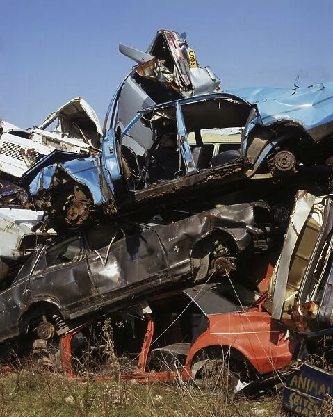 Scrapyard. Wrecked cars piled up in a scrapyard, circa 1980