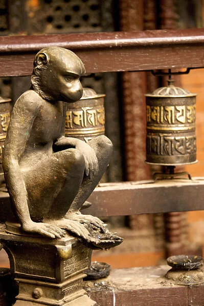 Sculpture of a seated monkey and prayer mills in the Golden Temple, a Buddhist temple, Patan, Nepal, Asia