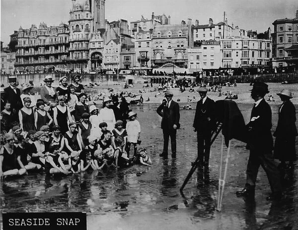 Smile. circa 1912: A seaside photographer taking a photograph of a crowd