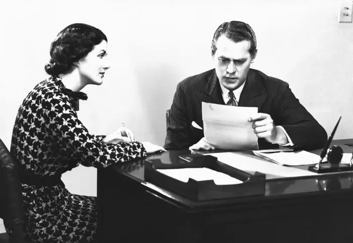 Framed Print : Secretary assisting businessman reading document at desk, (B&W) Framed Print : Secretary assisting businessman reading document at desk, (B&W)