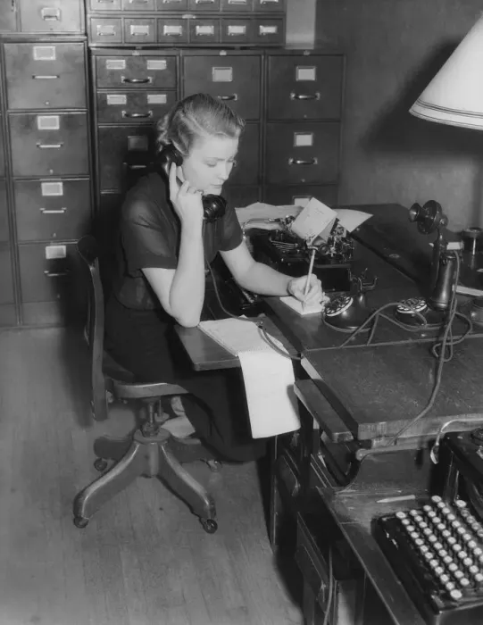 Framed Print : Secretary sitting at desk behind typewriter, on phone taking message Framed Print : Secretary sitting at desk behind typewriter, on phone taking message