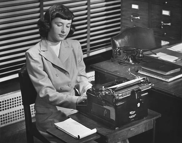 Secretary typing in office, (B&W)