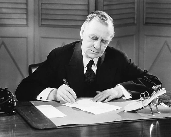 Senior businessman signing papers at desk, (B&W), close-up