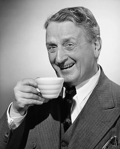 Senior man smiling with tea cup in hand, (B&W), portrait