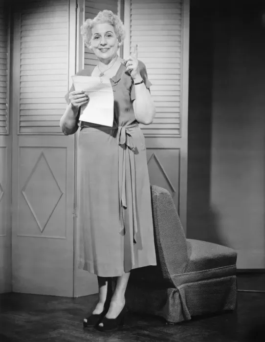 Framed Print : Senior woman holding sheet of paper, pointing up (B&W) Framed Print : Senior woman holding sheet of paper, pointing up (B&W)