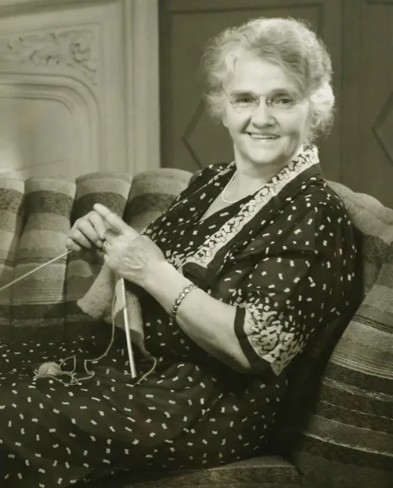 Framed Print : Senior woman knitting in living room, (B&W), portrait