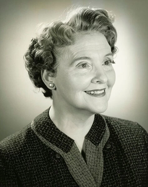 Senior woman smiling in studio, (B&W), close-up, portrait