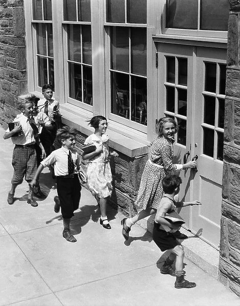 Seven children carrying books, about to enter schoolhouse