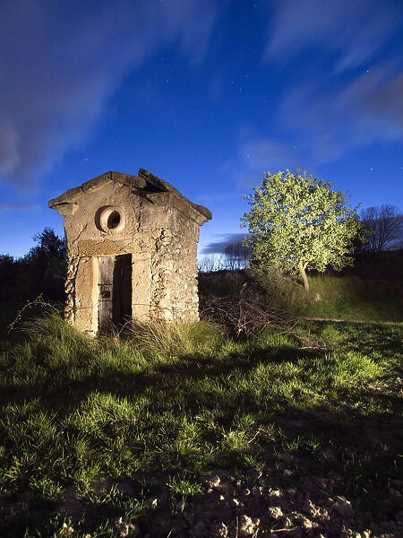 Shed of ancient stone of a well at dusk