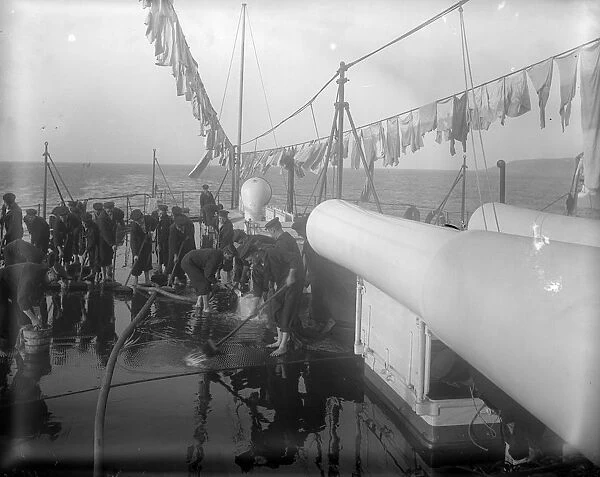 Shipshape. circa 1897: Sailors scrubbing the decks of their sailing ship