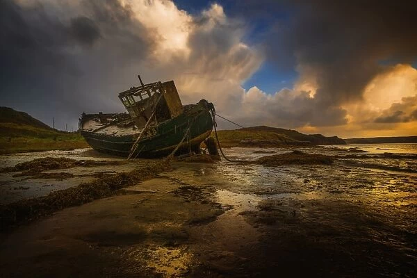 Shipwreck on beach at sunset