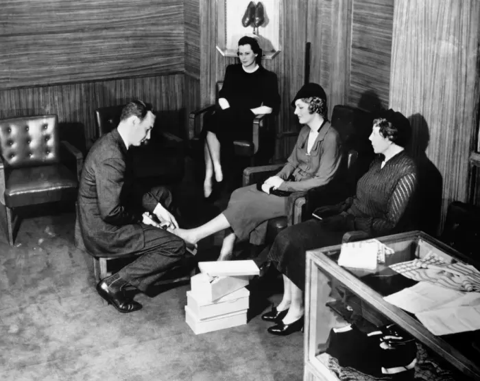 Framed Print : Shop clerk measuring clients foot (B&W), elevated view Framed Print : Shop clerk measuring clients foot (B&W), elevated view