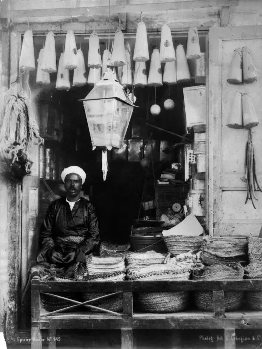 Framed Print : Shopfront. circa 1900: An African shopkeeper selling lanterns and household goods