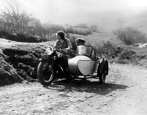 Sidecar. circa 1930: A couple take a ride in the countryside with their motorcycle