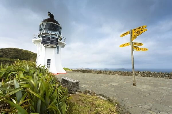 Signpost with distances and lighthouse at Cape Reinga, Cape Reinga, Northland Region, New Zealand