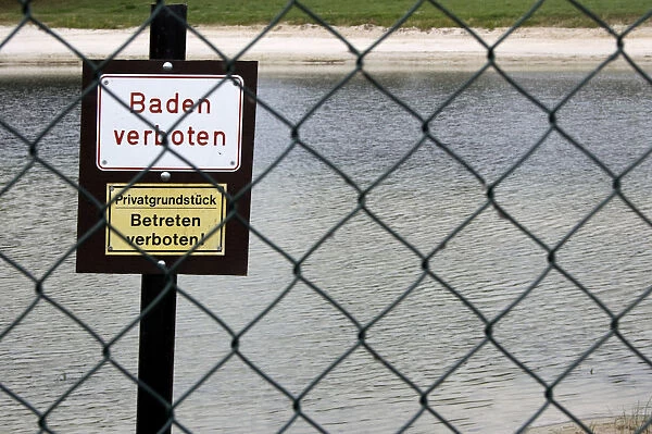 Two signs Baden verboten and Privatgrundstueck, Betreten verboten, German for Bathing prohibited and Private property, keep off, prohibition signs on the beach, wire mesh fence