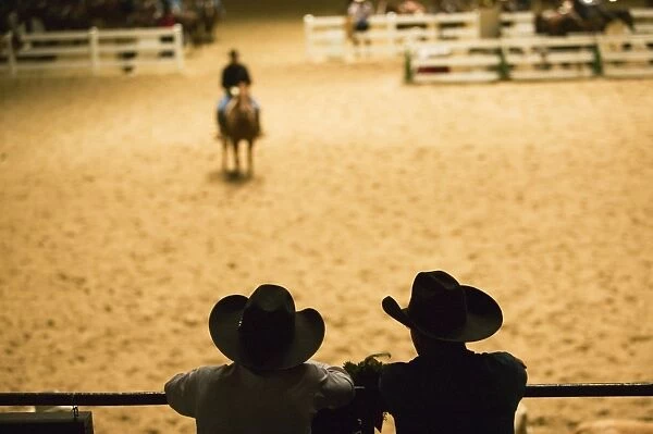 Silhouette of cowboys at indoor rodeo