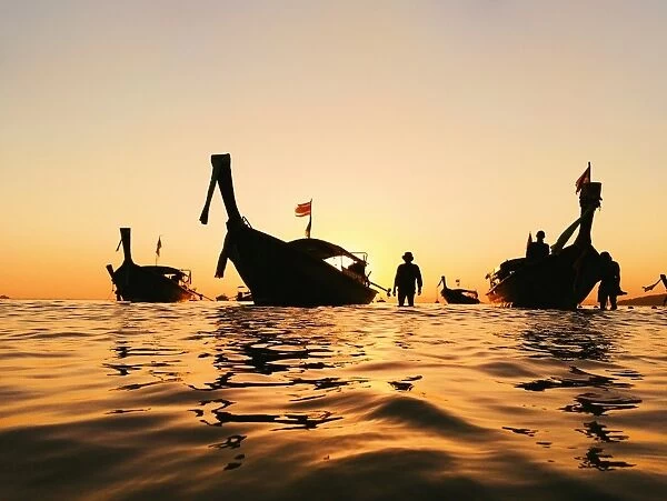 Silhouette of a longtail boat and fisherman at sunset in Krabi, Thailand