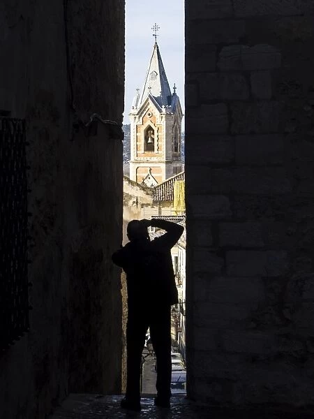 Silhouette of a person extracting a photo in a narrow alley