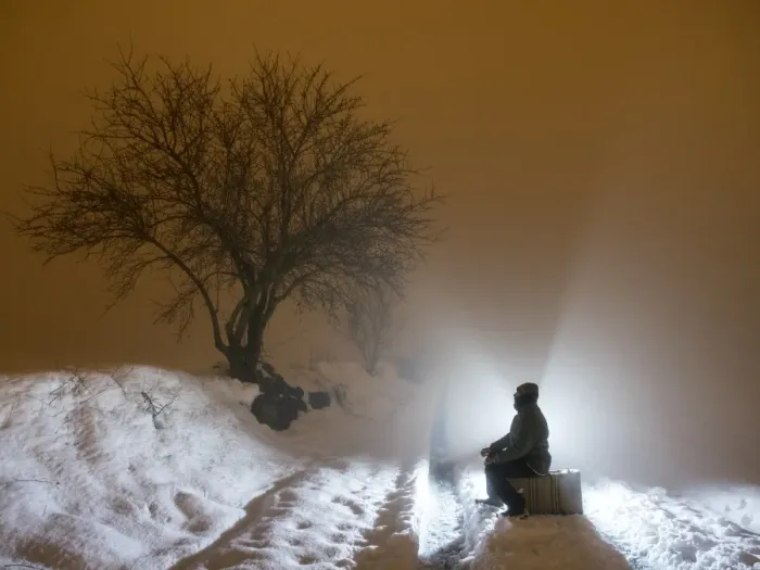 Framed Print : Silhouette of a person sitting on a suitcase resting, for a covered way of snow and fog during the night Framed Print : Silhouette of a person sitting on a suitcase resting, for a covered way of snow and fog during the night