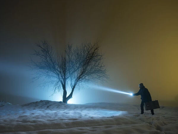 Silhouette of a person walking with a suitcase and a lantern, for a covered way of snow and fog during the night