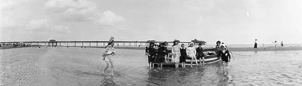 Skegness. circa 1905: Children paddling at Skegness