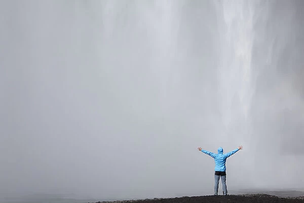 Skogafoss waterfall with a hiker, Skogar, South Iceland, Iceland, Europe