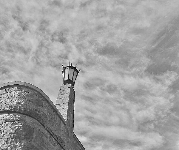 Sky Light. A black and white photo of a lamppost on the stone wall of Rocky