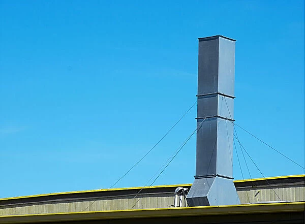 Sky Stack. A color photo of a tall air vent on the roof of a commercial