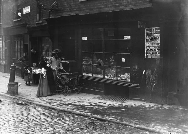Slum Life. 1907: Women pushing a pram past a bakery window in Little Italy