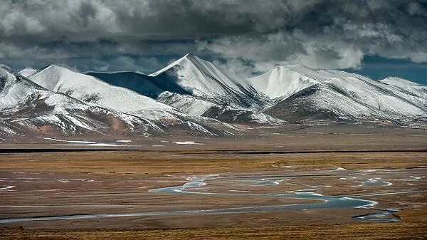 Tibet. Small creeks passing through Tibet highland with snow capped mountain in background
