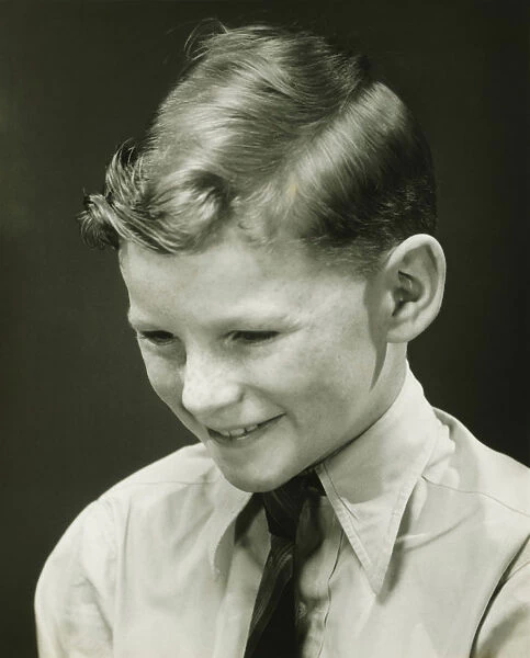 Smiling boy (10-11) posing in studio, (B&W), portrait