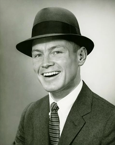 Smiling man in fedora hat posing un studio, (B&W), close-up, portrait
