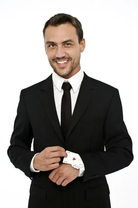 Framed Print : Smiling man wearing a suit pulling several aces out of his sleeve