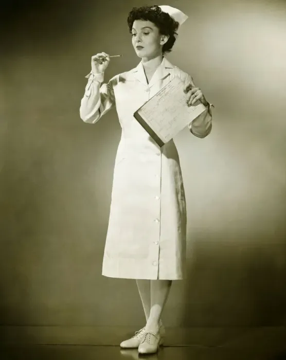 Framed Print : Smiling nurse holding thermometer and files in studio, (B&W), portrait Framed Print : Smiling nurse holding thermometer and files in studio, (B&W), portrait