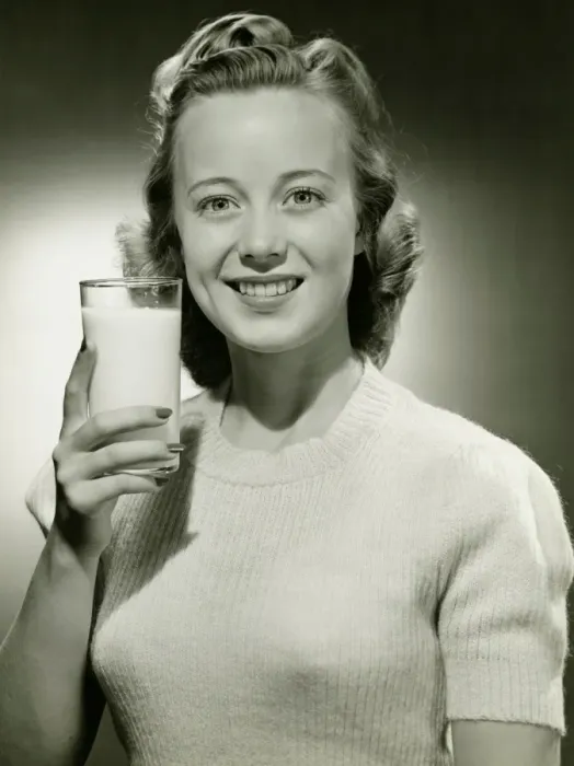 Framed Print : Smiling woman holding glass of milk in studio, (B&W), portrait Framed Print : Smiling woman holding glass of milk in studio, (B&W), portrait