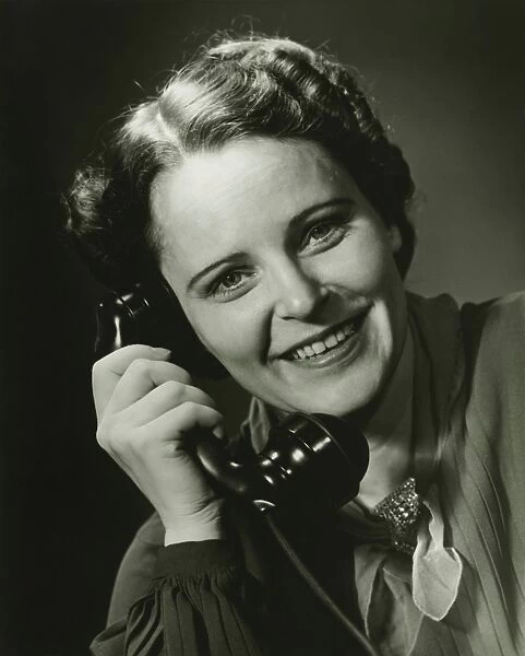 Smiling woman on phone posing in studio, (B&W), close-up, portrait