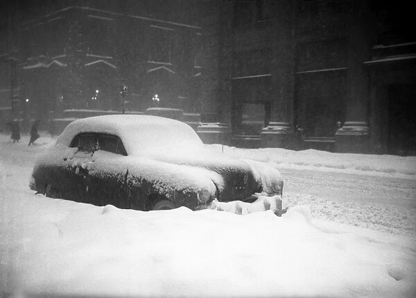 Snow capped car on street in blizzard, (B&W)