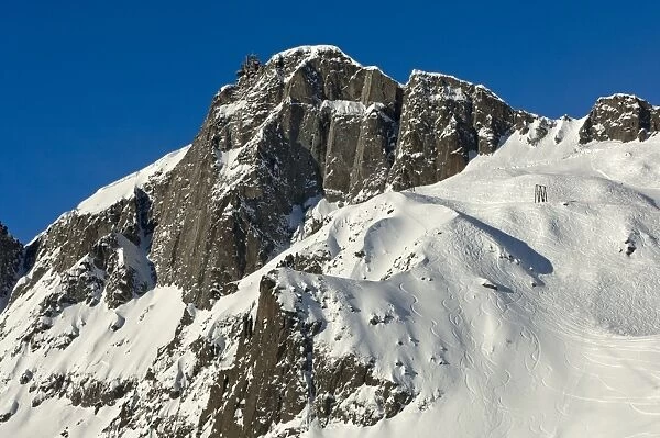 Snow-covered peaks of Le Brevent Mountain with the mountain station of the cable car, tracks from deep snow riders on the steep slopes, Chamonix ski resort, France, Europe